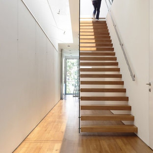 Imagen de escalera suspendida, minimalista, de tamaño medio, sin contrahuella, con barandilla de vidrio y escalones de madera