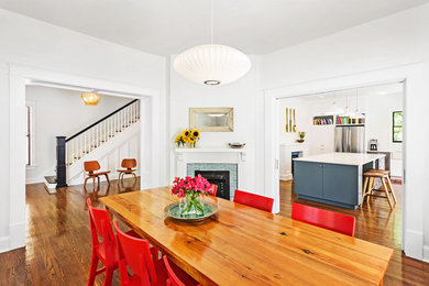 Inspiration for a mid-sized transitional medium tone wood floor enclosed dining room remodel in Other with white walls, a corner fireplace and a tile fireplace