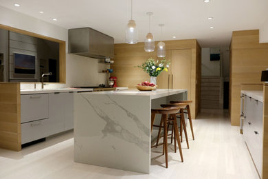 Modelo de cocina moderna con armarios con paneles lisos, puertas de armario grises, salpicadero blanco, salpicadero de azulejos de porcelana y dos o más islas