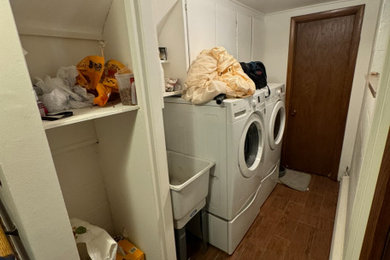 Mid-sized arts and crafts galley porcelain tile and brown floor laundry room photo in Detroit with raised-panel cabinets, wood countertops and a stacked washer/dryer