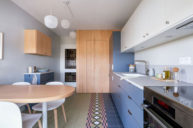 Cette image montre une cuisine linéaire design de taille moyenne avec un placard à porte plane, des portes de placard bleues, carreaux de ciment au sol, un sol multicolore, un plan de travail gris et machine à laver.