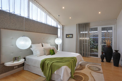 This is an example of a mid-sized contemporary master bedroom in Adelaide with beige walls and light hardwood floors.