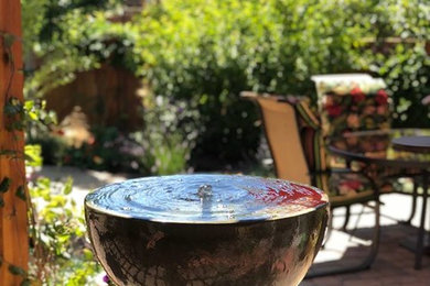 This is an example of a small southwestern drought-tolerant and full sun backyard concrete paver water fountain landscape in Portland for summer.