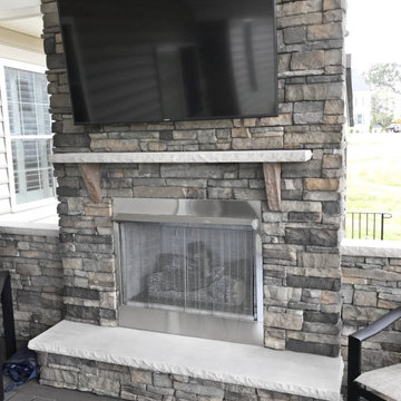 Custom Azek Dark Hickory porch with fireplace and Eldorado stone in New Market
