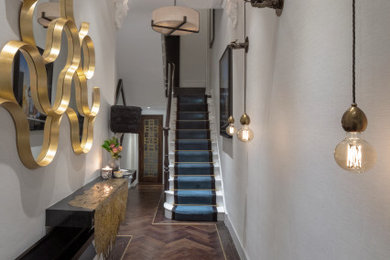 This is an example of a medium sized victorian hallway in London with white walls, dark hardwood flooring, a single front door, a black front door, brown floors and feature lighting.