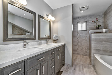 Mid-sized transitional master bathroom in Toronto with shaker cabinets, distressed cabinets, a corner tub, a curbless shower, a two-piece toilet, gray tile, porcelain tile, grey walls, porcelain floors, an undermount sink and solid surface benchtops.