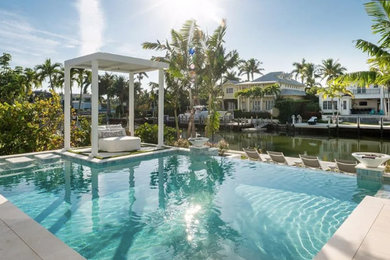 Example of a mid-sized beach style backyard custom-shaped and concrete paver infinity and privacy pool design in Other