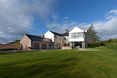 Large contemporary single-wall open plan kitchen in Belfast with an integrated sink, flat-panel cabinets, white cabinets, engineered stone countertops, grey splashback, stone slab splashback, stainless steel appliances, porcelain flooring and an island.