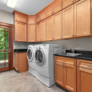 Photo of a medium sized classic l-shaped separated utility room in Other with a built-in sink, recessed-panel cabinets, light wood cabinets, granite worktops, beige walls, porcelain flooring, a side by side washer and dryer, beige floors and black worktops.