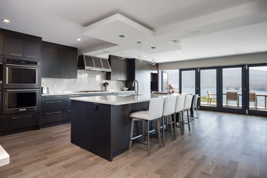 Design ideas for an expansive contemporary l-shaped open plan kitchen in Vancouver with an undermount sink, flat-panel cabinets, dark wood cabinets, quartzite benchtops, grey splashback, marble splashback, stainless steel appliances, medium hardwood floors, with island and brown floor.