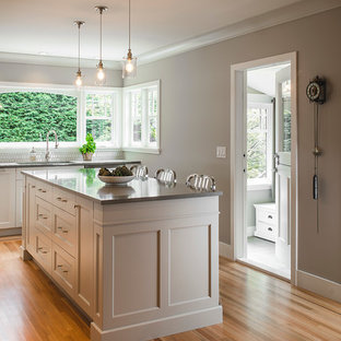 Mid-sized transitional kitchen pantry photos - Example of a mid-sized transitional l-shaped medium tone wood floor kitchen pantry design in Vancouver with an undermount sink, recessed-panel cabinets, gray cabinets, quartz countertops, white backsplash, ceramic backsplash, stainless steel appliances and an island