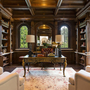 Modelo de despacho clásico, grande, con paredes marrones, suelo de madera oscura, escritorio independiente, suelo marrón, chimenea tradicional y marco de chimenea de madera