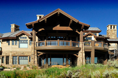 Photo of an expansive contemporary two-storey beige house exterior in Denver with stone veneer and a hip roof.