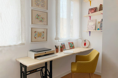 Ejemplo de estudio bohemio de tamaño medio con paredes blancas, suelo de madera en tonos medios y escritorio empotrado