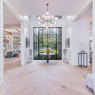 ロサンゼルスの巨大な両開きドアコンテンポラリースタイルのおしゃれな玄関ロビー (白い壁、淡色無垢フローリング、金属製ドア) の写真