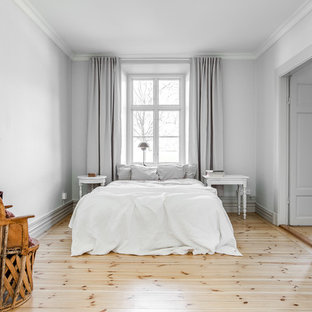 Idéer för att renovera ett skandinaviskt huvudsovrum, med vita väggar och ljust trägolv
