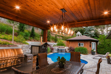 Example of a mid-sized minimalist backyard stone patio kitchen design in Toronto with a roof extension