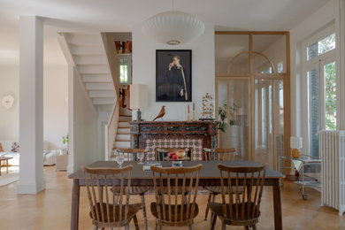 Inspiration pour une salle à manger nordique avec un mur blanc, parquet clair, une cheminée standard, un manteau de cheminée en carrelage et un sol beige.