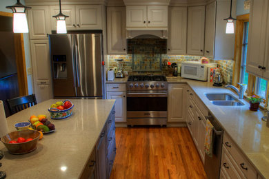 Mid-sized elegant l-shaped medium tone wood floor eat-in kitchen photo in Kansas City with stainless steel appliances and an island