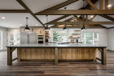 Inspiration for a large farmhouse galley laminate floor, brown floor and exposed beam open concept kitchen remodel in Seattle with a farmhouse sink, flat-panel cabinets, light wood cabinets, quartzite countertops, white backsplash, subway tile backsplash, stainless steel appliances, an island and gray countertops