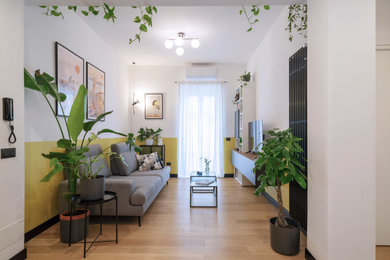 Immagine di un soggiorno minimalista di medie dimensioni e aperto con pareti gialle, parquet chiaro, parete attrezzata e pavimento marrone
