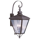 Livex Lighting - Cambridge Outdoor Wall Lantern, Bronze - This stylish bronze outdoor wall lantern is a great way to update your home's exterior decor. A flat metal curved arm attaches the solid brass decorative housing to the square backplate while clear water glass protects the four bulbs.