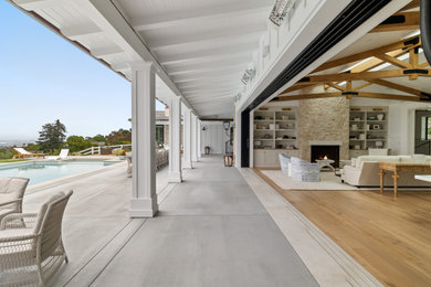 Living room - large cottage open concept light wood floor and exposed beam living room idea in Los Angeles with a standard fireplace, a stone fireplace and white walls