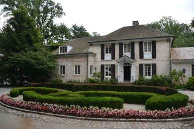 Large traditional two-storey brick white house exterior in Philadelphia with a hip roof and a shingle roof.