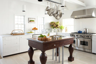 This is an example of a traditional l-shaped kitchen in Boston with white cabinets, marble benchtops, white splashback, stainless steel appliances, with island, a single-bowl sink, subway tile splashback and light hardwood floors.