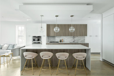 Trendy l-shaped medium tone wood floor and brown floor kitchen photo in Chicago with an undermount sink, flat-panel cabinets, gray cabinets, white backsplash, stainless steel appliances, an island and white countertops