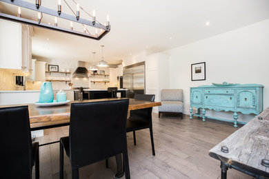 Example of a trendy medium tone wood floor and gray floor kitchen design in Other with shaker cabinets, white cabinets, quartz countertops, white backsplash, stone tile backsplash, black appliances and white countertops