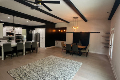 Example of a large eclectic open concept light wood floor and exposed beam living room design in Atlanta with black walls