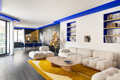 Imagen de sala de estar con biblioteca abierta contemporánea de tamaño medio sin chimenea con paredes blancas, suelo laminado, suelo gris y televisor colgado en la pared