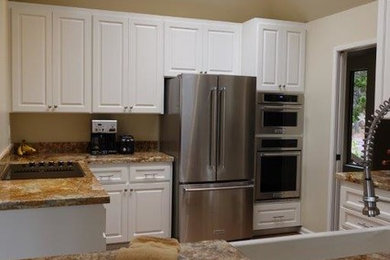 Example of a mid-sized trendy l-shaped dark wood floor enclosed kitchen design in San Francisco with a farmhouse sink, recessed-panel cabinets, white cabinets, quartzite countertops, white backsplash, stainless steel appliances and no island