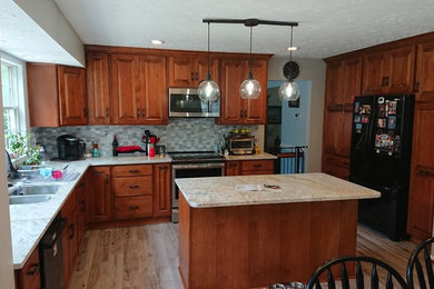Inspiration for a mid-sized timeless l-shaped porcelain tile kitchen remodel in Baltimore with raised-panel cabinets, medium tone wood cabinets, granite countertops, ceramic backsplash, stainless steel appliances and an island