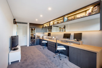 Photo of a mid-sized contemporary study room in Sydney with beige walls, carpet, a built-in desk and grey floor.
