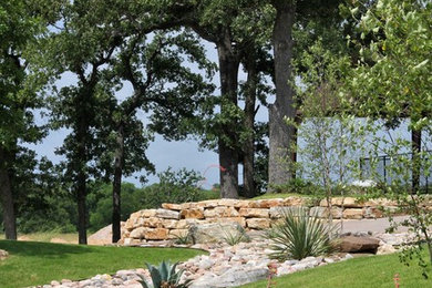 Photo of a huge rustic drought-tolerant hillside gravel retaining wall landscape in Austin.