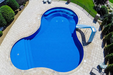 Example of a mid-sized classic backyard stone and custom-shaped lap water slide design in Other