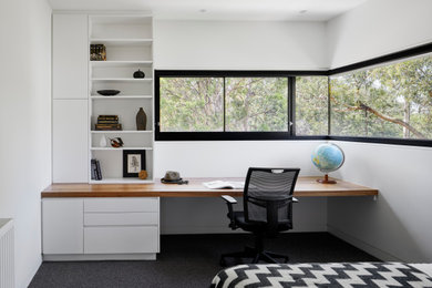 Mid-sized contemporary study room in Melbourne with white walls, carpet, a built-in desk and grey floor.