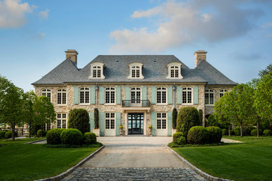 Design ideas for a two-storey beige house exterior in New York with stone veneer, a hip roof and a tile roof.