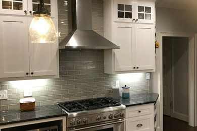 Example of a mid-sized classic u-shaped dark wood floor and brown floor open concept kitchen design in Atlanta with a double-bowl sink, shaker cabinets, white cabinets, granite countertops, subway tile backsplash, stainless steel appliances and a peninsula