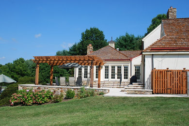 Patio - large traditional backyard stone patio idea in Philadelphia with a pergola