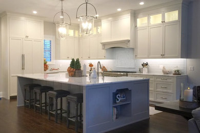 Inspiration for a large transitional l-shaped eat-in kitchen in Orlando with a farmhouse sink, shaker cabinets, white cabinets, marble benchtops, white splashback, subway tile splashback, stainless steel appliances, dark hardwood floors, with island and brown floor.