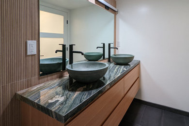 Small trendy master beige tile and porcelain tile porcelain tile, black floor, double-sink and wainscoting bathroom photo in Los Angeles with flat-panel cabinets, medium tone wood cabinets, beige walls, a vessel sink, quartzite countertops, green countertops and a floating vanity