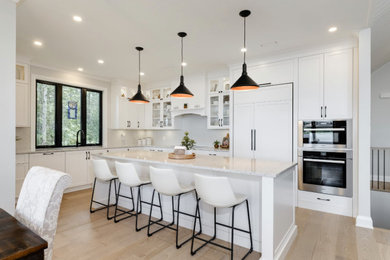 Design ideas for a contemporary l-shaped eat-in kitchen in Ottawa with an undermount sink, shaker cabinets, white cabinets, quartz benchtops, white splashback, ceramic splashback, black appliances, light hardwood floors, with island and white benchtop.