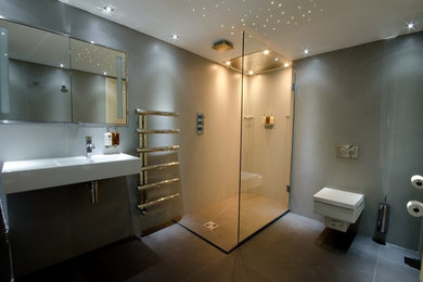 Contemporary master bathroom in London with an open shower, a wall-mount toilet, gray tile, porcelain tile, grey walls, porcelain floors and a wall-mount sink.
