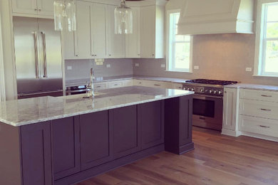 Inspiration for a large modern l-shaped medium tone wood floor eat-in kitchen remodel in Jacksonville with a farmhouse sink, shaker cabinets, white cabinets, quartz countertops, white backsplash, glass tile backsplash, stainless steel appliances and an island