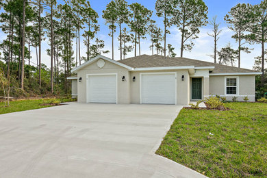 Inspiration for a mid-sized timeless beige one-story stucco exterior home remodel in Orlando with a shingle roof