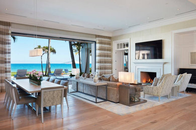 Example of a huge beach style open concept medium tone wood floor, brown floor and wallpaper living room design in Miami with beige walls, a standard fireplace, a stone fireplace and a wall-mounted tv