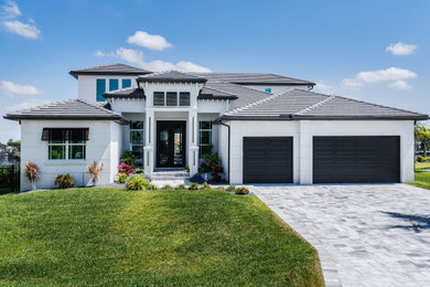 Huge beach style white two-story house exterior photo in Miami with a hip roof, a tile roof and a gray roof
